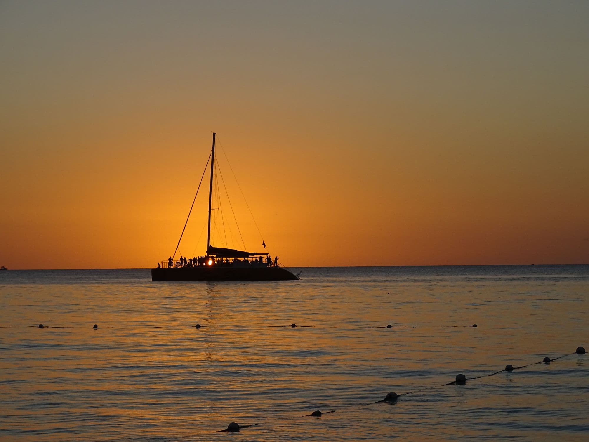 Catamaran silhouetted against a golden Negril sunset